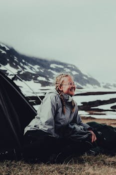 A woman enjoying a winter camping trip in snowy Hemavan, Sweden, smiling by the tent.