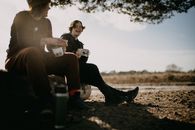 Woman in Black Pants and Black Boots Sitting on Black Plastic Trash Bin