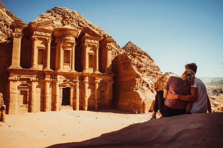 A Couple Sitting In Front Of A Historical Building