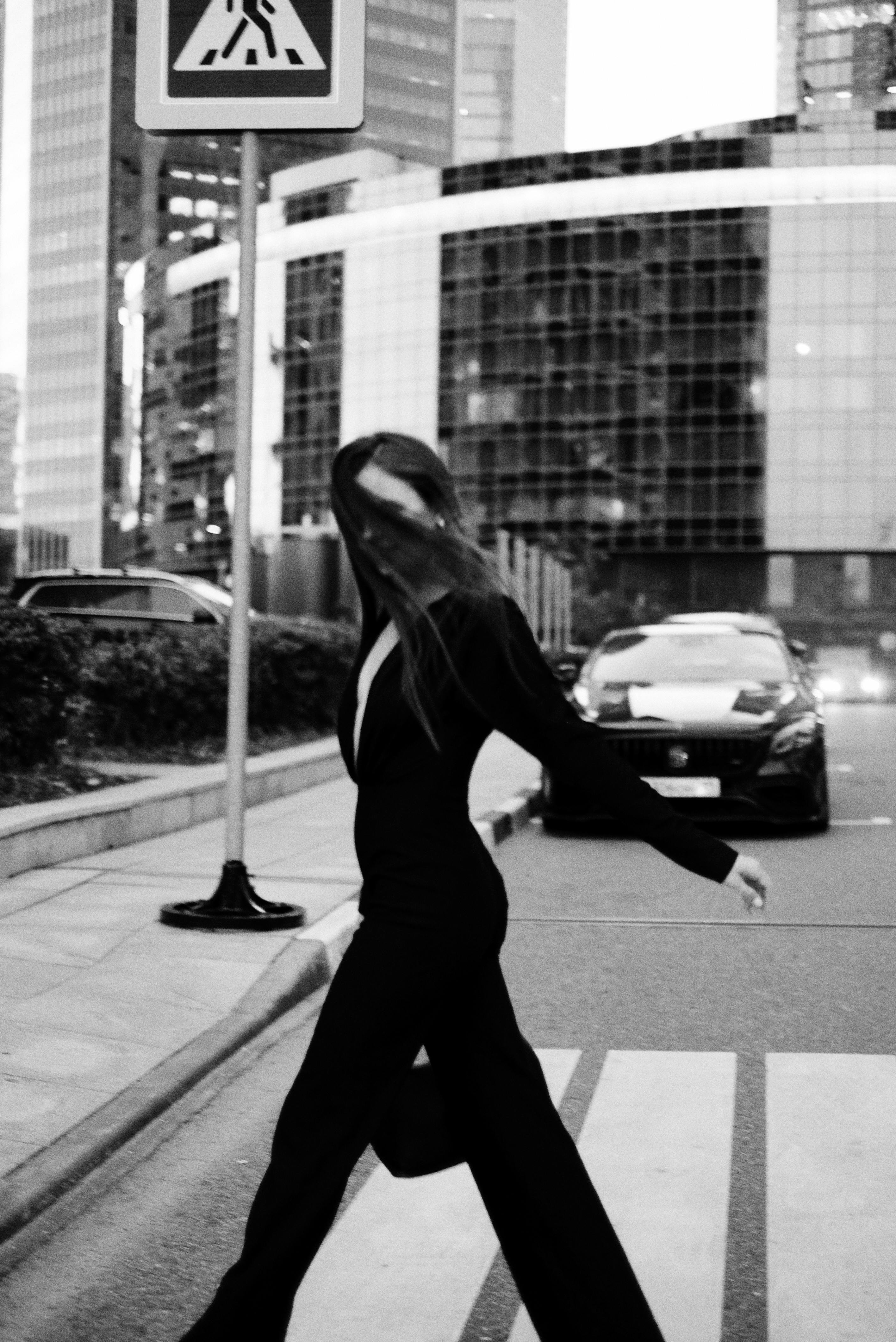 Elegant woman in black attire crossing a street in Moscow's urban setting, embodying city fashion.