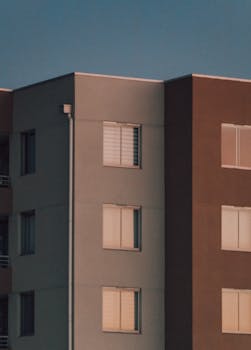 Low-angle view of a modern apartment building facade at sunset with clear sky.
