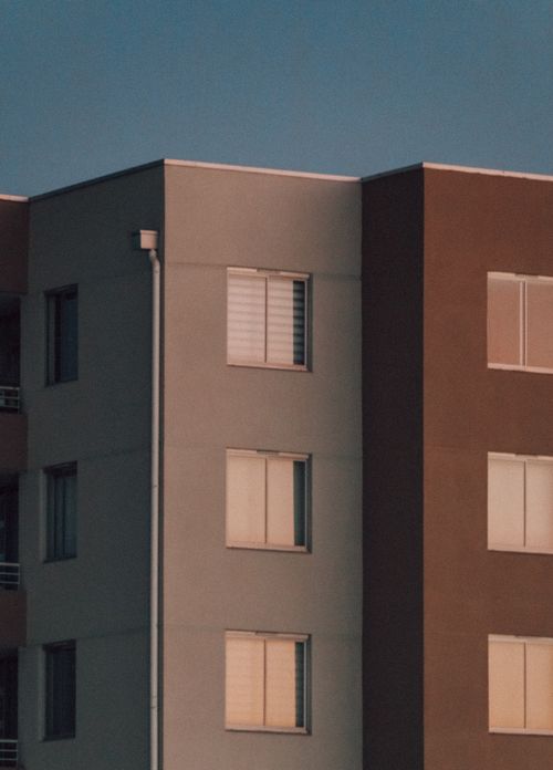 Free Low-angle view of a modern apartment building facade at sunset with clear sky. Stock Photo