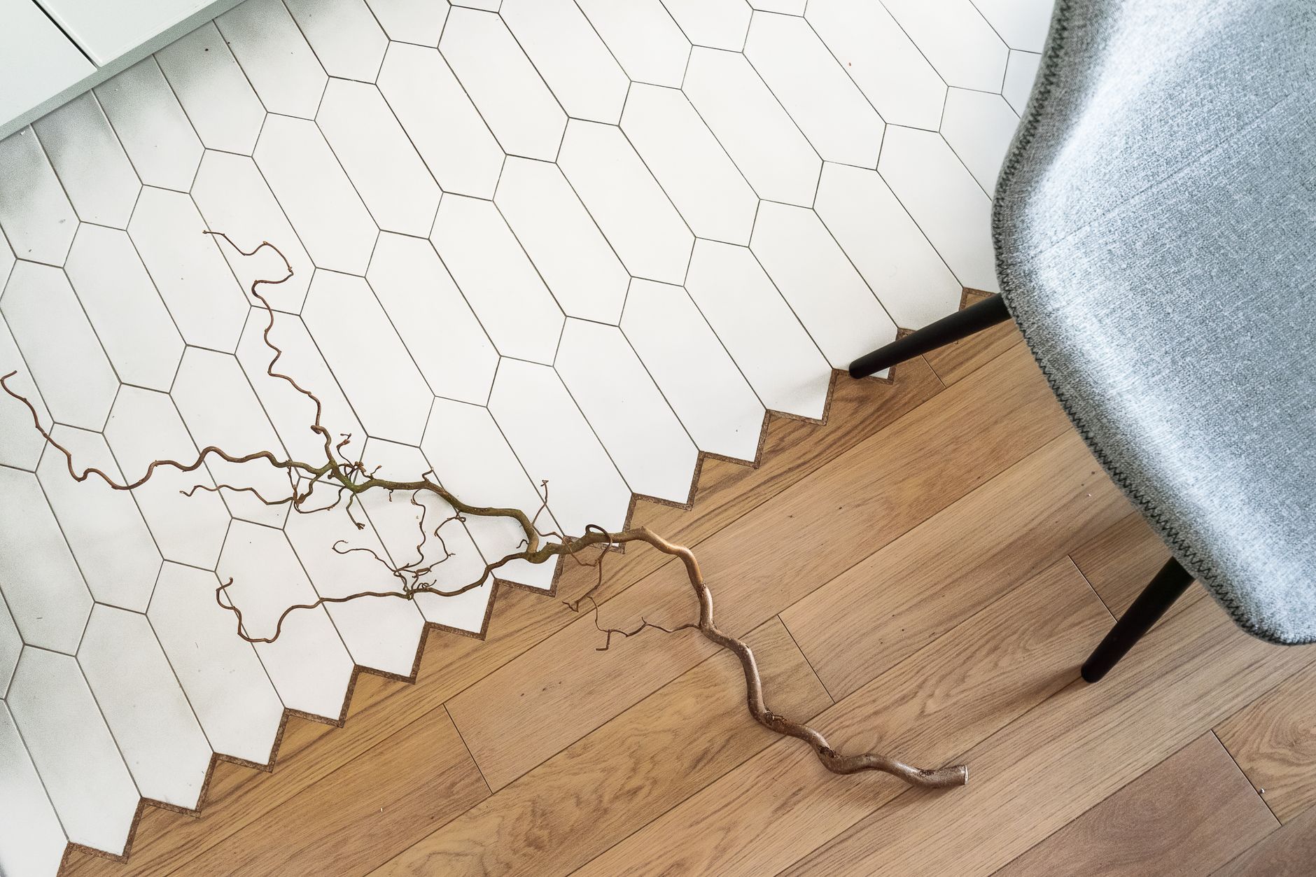 Overhead view of a modern interior with wooden and tile flooring featuring a decorative branch.