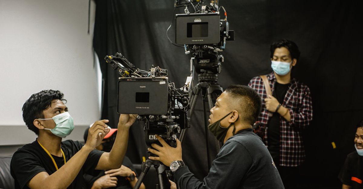 Team of videographers setting up professional camera equipment in a studio