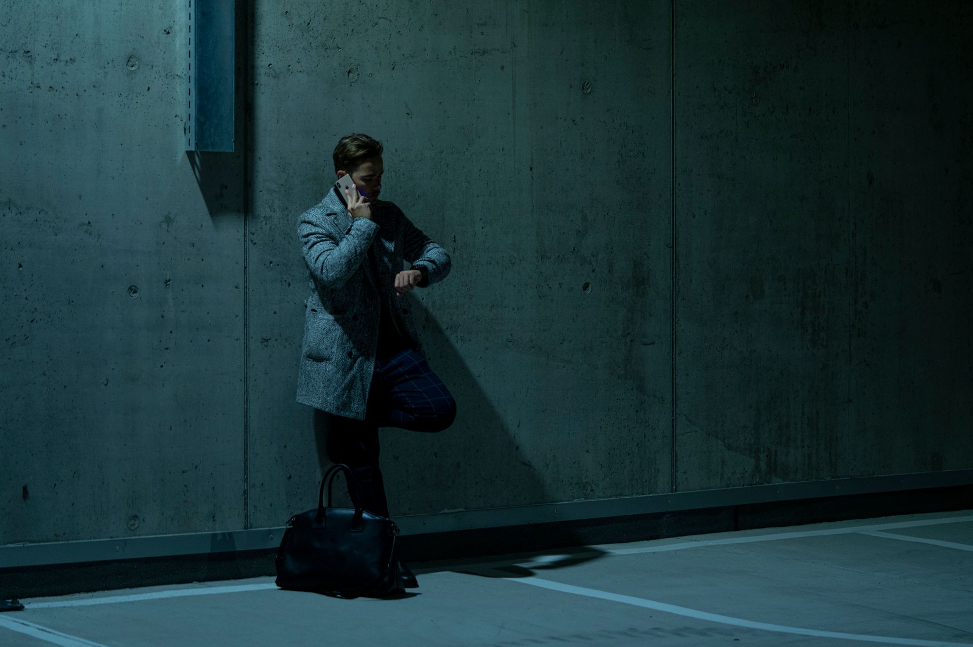 Man on Phone Call Leaning on Wall and Looking at his Watch