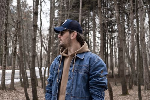 Free Man wearing a denim jacket and cap in a forest, İstanbul, Turkey. Casual, reflective mood. Stock Photo