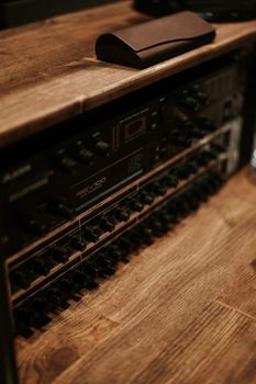 Close-up view of a vintage amplifier on a wooden shelf featuring control knobs and rustic ambiance.