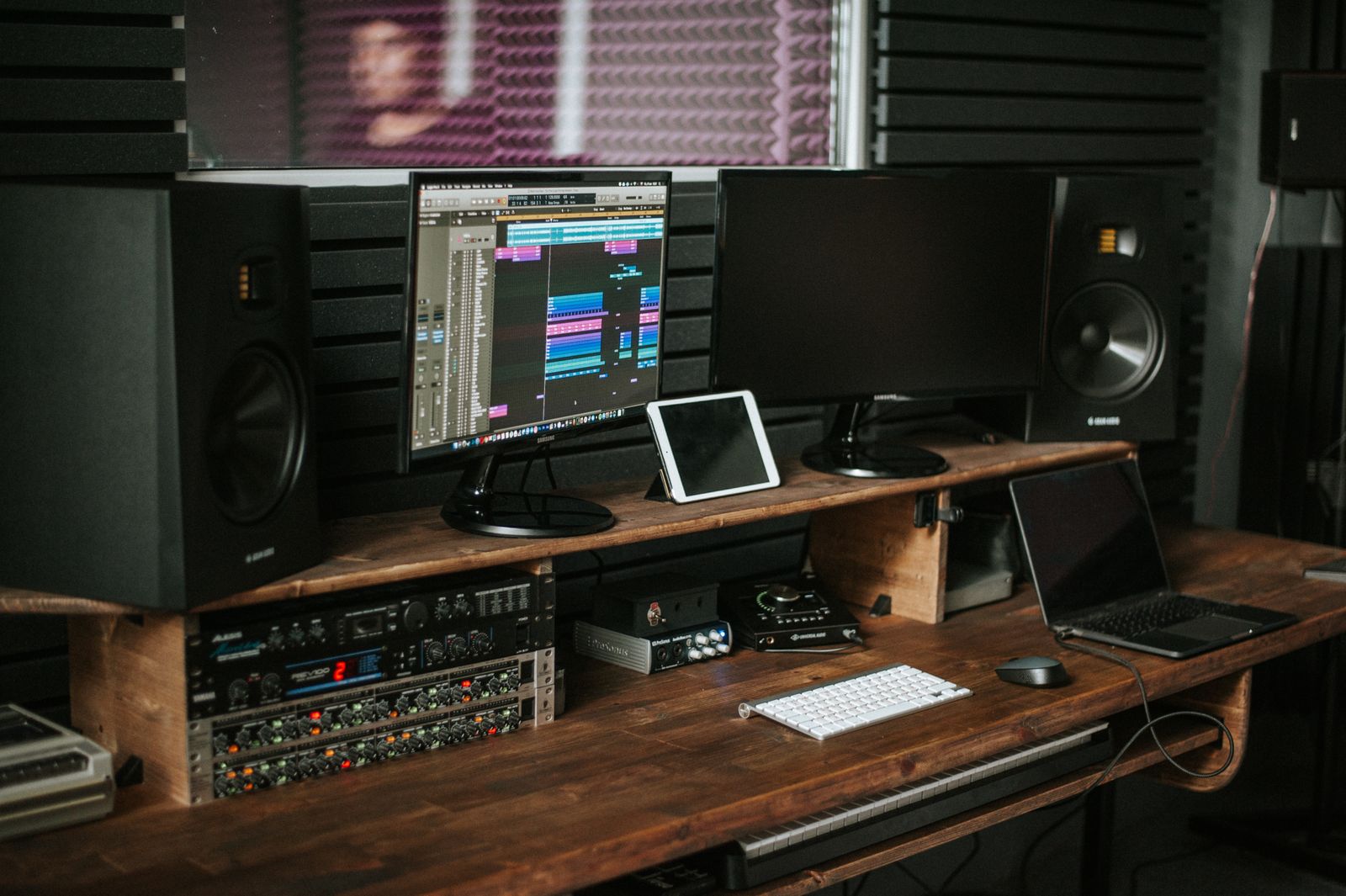 Music production workspace with speakers, monitors, and a desk.