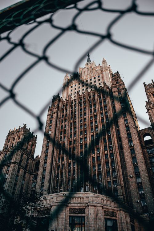 Free Gothic skyscraper in Moscow framed by a chain link fence, low angle view. Stock Photo