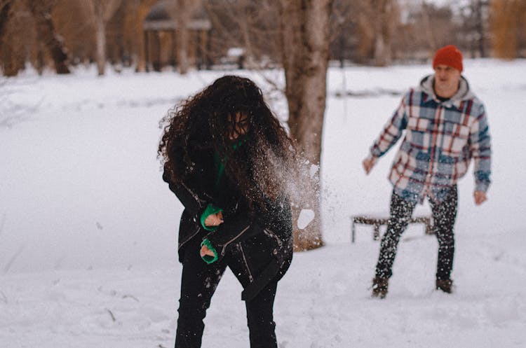 A Man Throwing A Snow Ball To A Woman