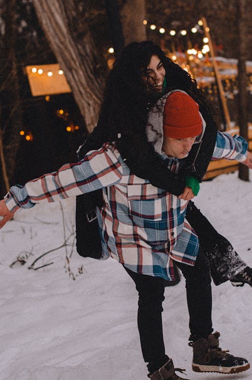 A Man Carrying a Woman on his Back on a Snow Covered Ground