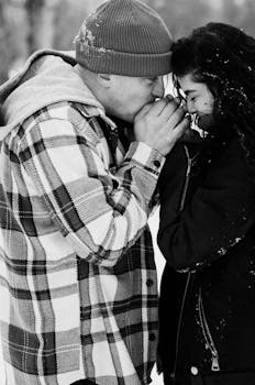 A loving couple embraces in winter, capturing warmth and affection against a snowy backdrop.