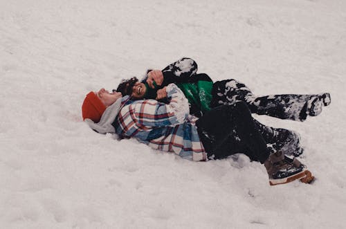 A Couple Lying Down on a Snow Covered Ground