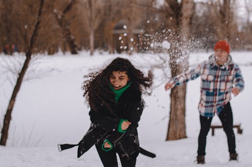 A Man and Woman Having Fun while Playing Snow