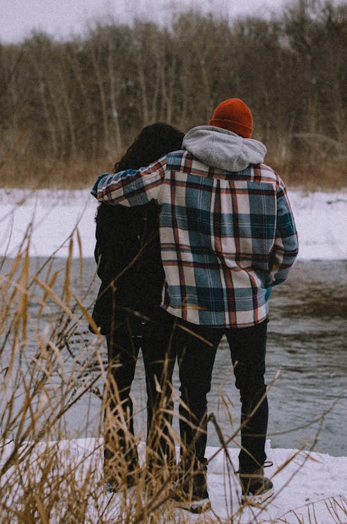 A Back View of a Couple Standing on a Snow Covered Ground