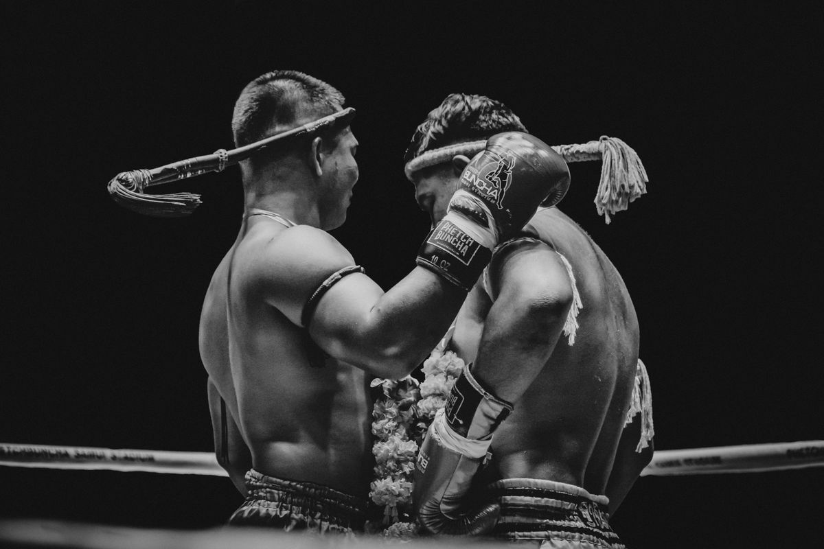 Zwei Muay-Thai-Kämpfer im Clinch, einer trägt das traditionelle Kopfband Mongkol