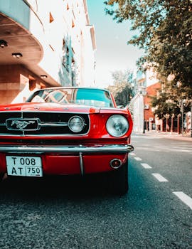 Iconic red Ford Mustang parked on a sunny urban street with classic architecture.