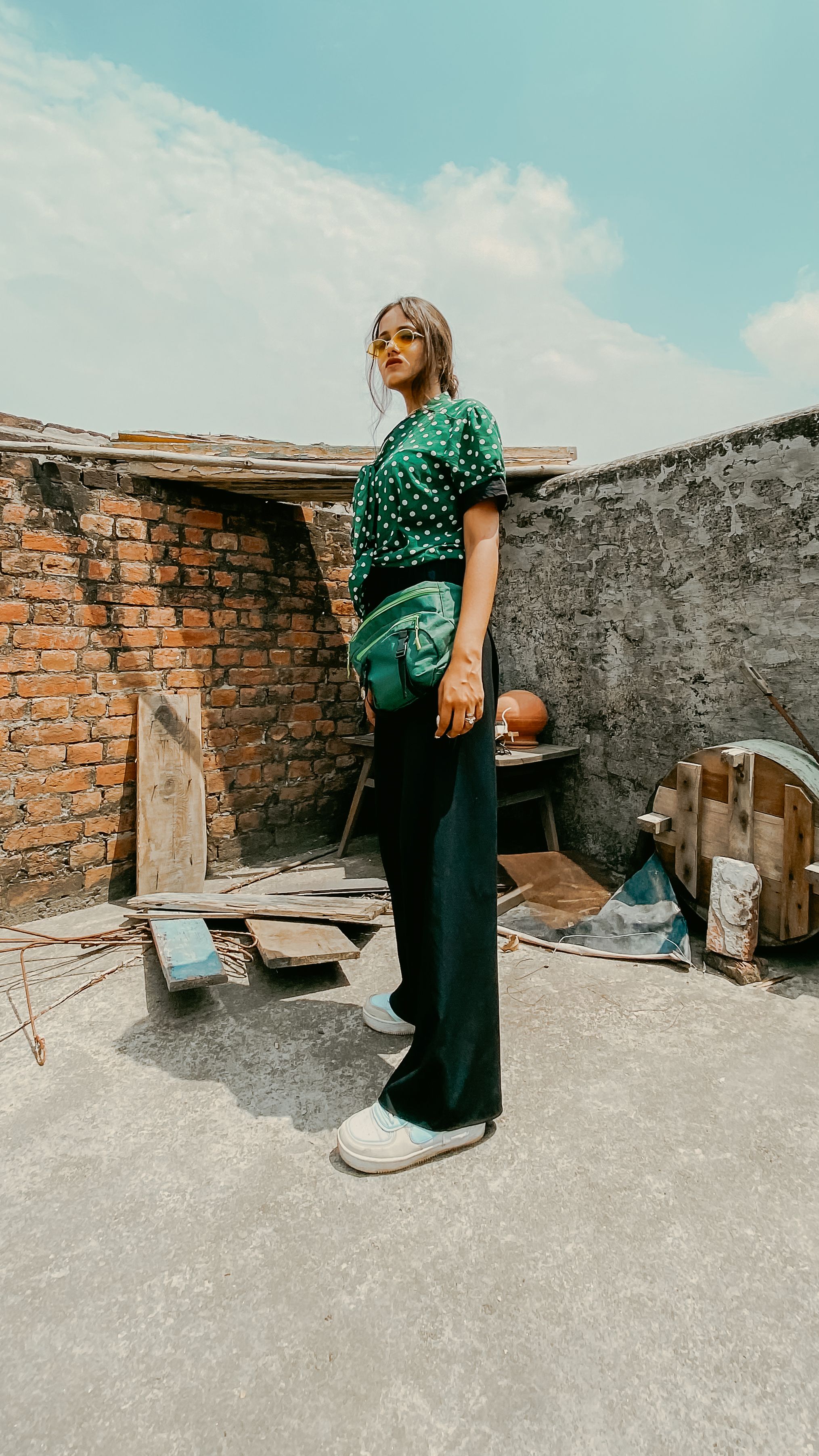 Fashion shoot showcasing a woman in a polka dot top standing confidently on an urban rooftop.