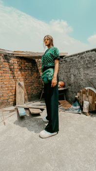 Fashion shoot showcasing a woman in a polka dot top standing confidently on an urban rooftop.