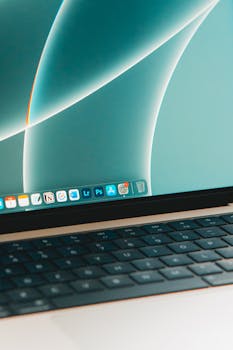 Close-up shot of a laptop keyboard and screen displaying various software apps, ideal for tech themes.