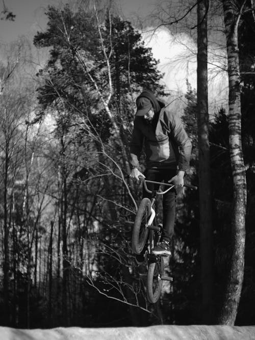 A Grayscale Photo of a Man Riding a Bicycle