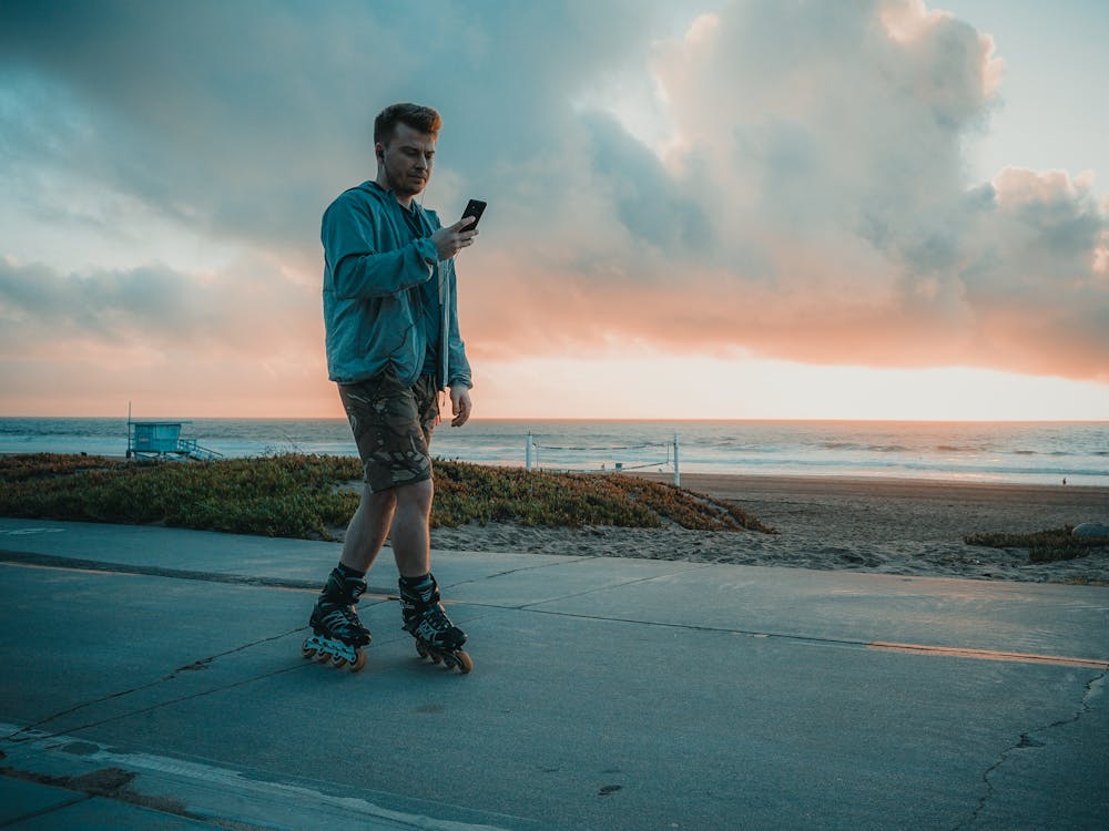 A Man Wearing Roller Blades while Using Smartphone 