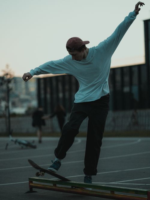 Free Teenage skater skillfully balancing on a skateboard ramp during twilight in an urban park. Stock Photo