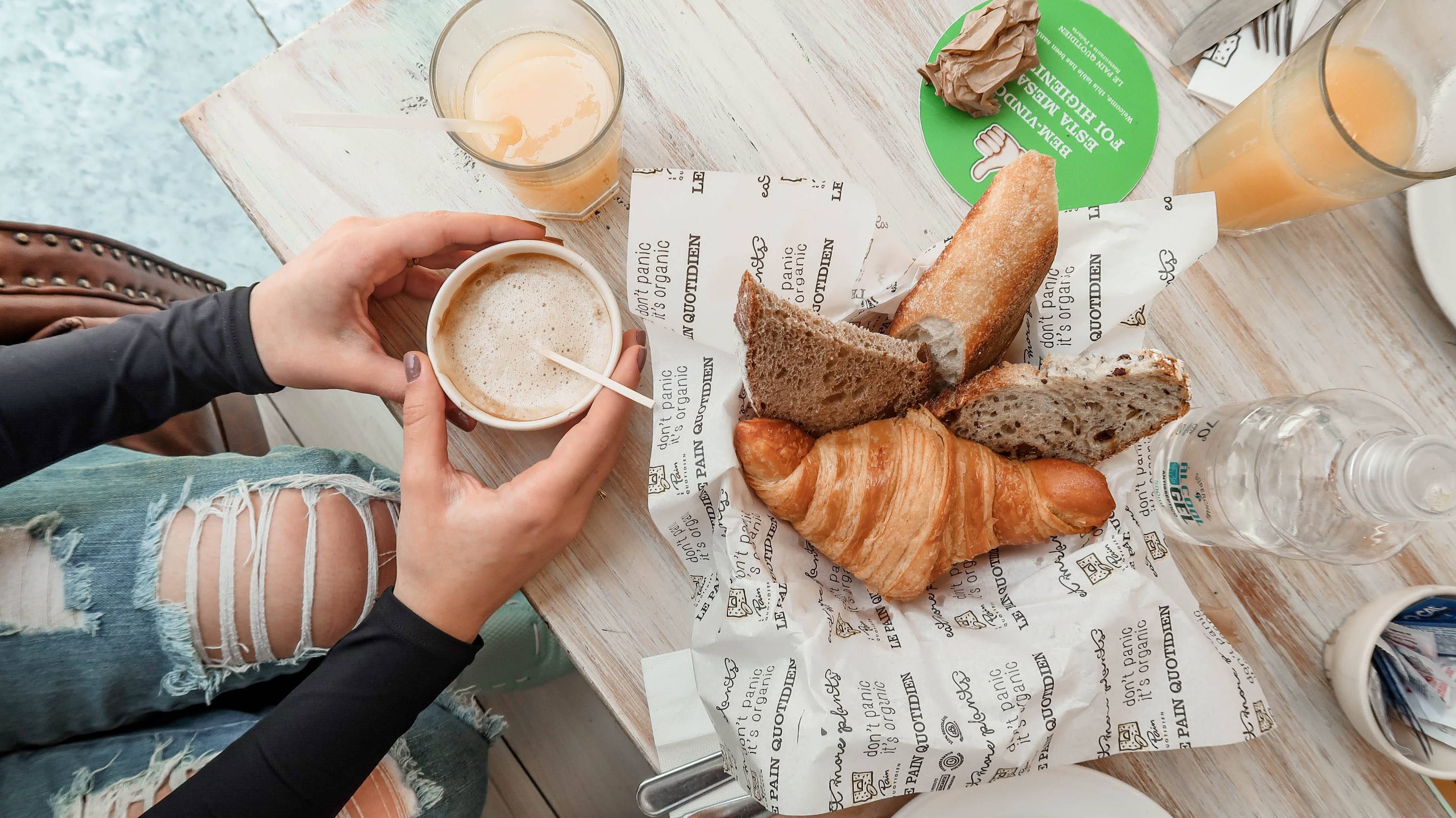 Overhead view of a casual café table with coffee, juice, and pastries.