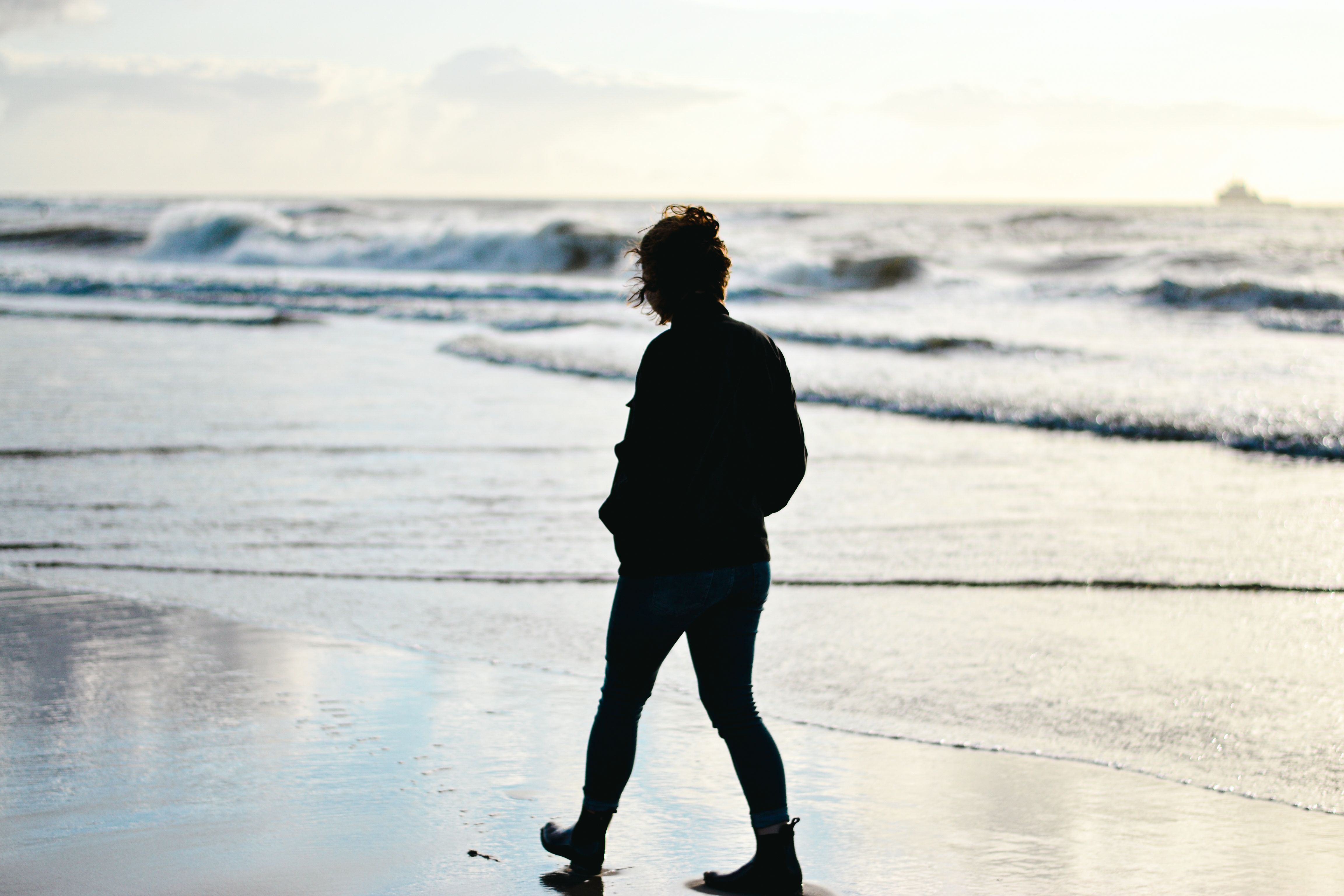 Silhouette of a Woman Walking on the Sea Shore · Free Stock Photo