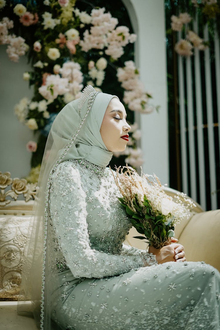 A Woman In Hijab Holding A Flower While Eyes Closed