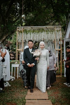 Beautiful Asian couple walking down the aisle during an outdoor wedding ceremony.