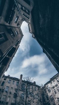 Upward perspective of urban buildings framing a dramatic sky overhead.