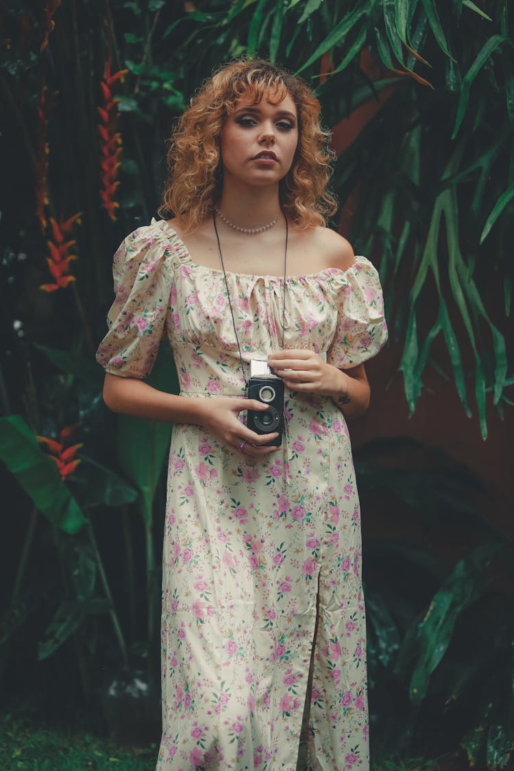 A Woman In White And Pink Floral Dress With A Camera