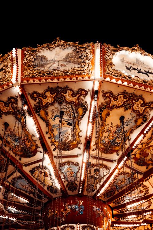 Free A close-up view of an illuminated ornate carousel featuring intricate artwork and detailed design under a night sky. Stock Photo