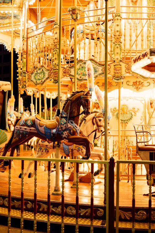 Free Vibrant carousel glowing with lights at a nighttime fair, showcasing colorful horses and ornate designs. Stock Photo