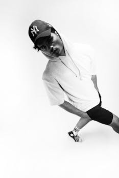 Black and white portrait of a young man in sporty attire, striking a unique pose.