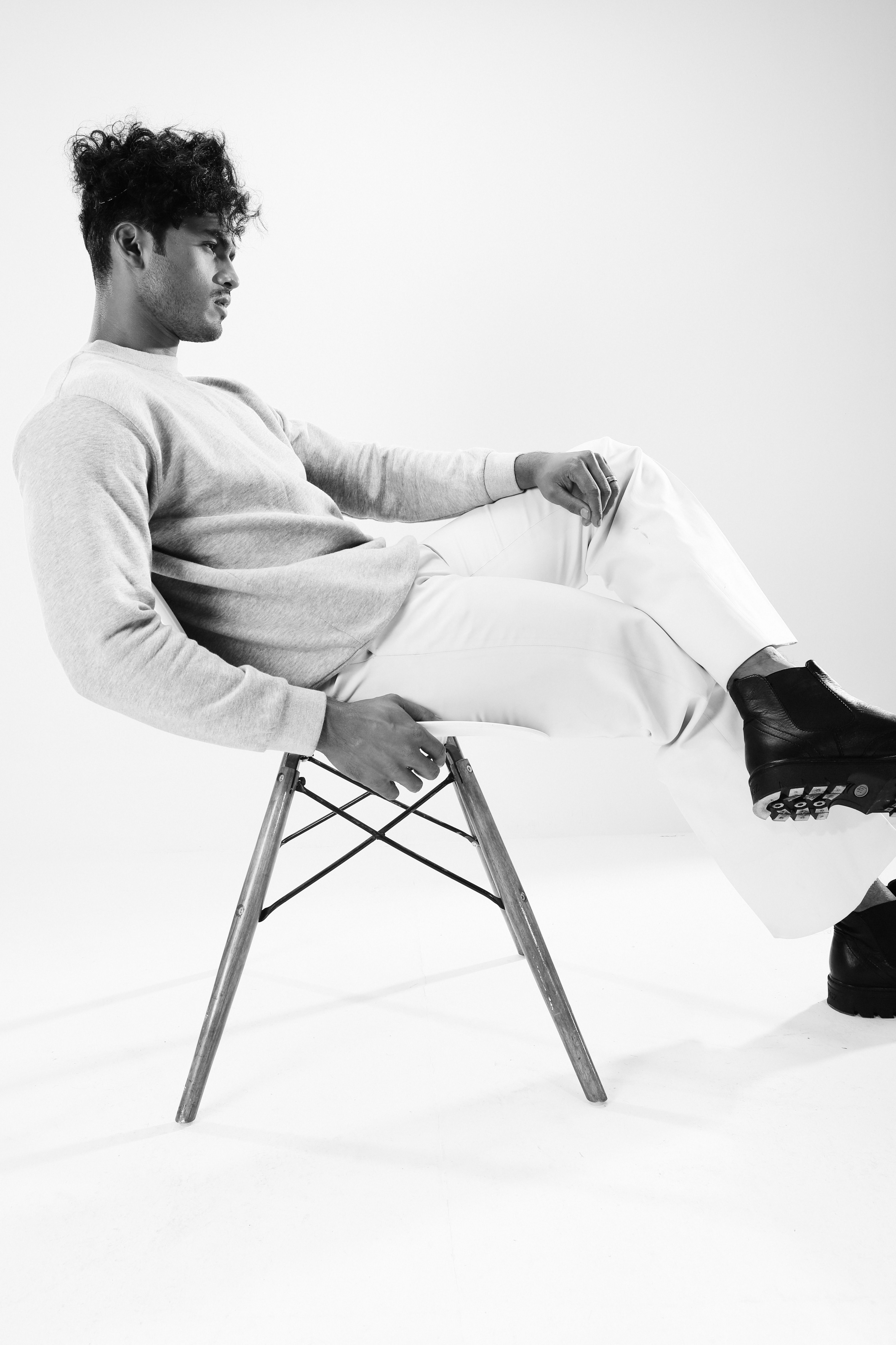 Sophisticated black and white portrait of a man leaning stylishly on a chair.