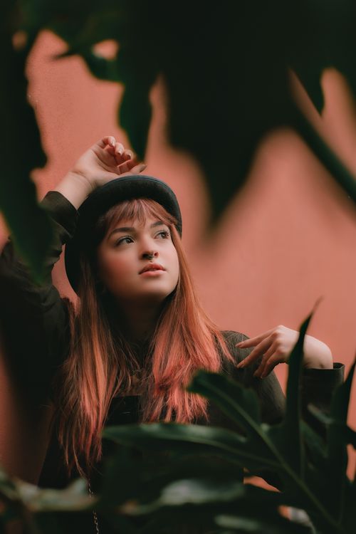 Free Artistic portrait of a redhead woman in a beret surrounded by lush greenery. Stock Photo