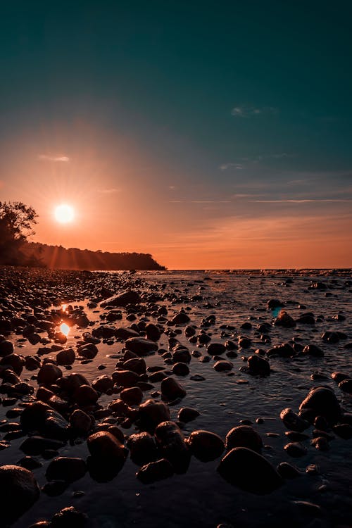 Free Photo Of Rock Rubles Beside Calm Body Of Water during Golden Hour Stock Photo