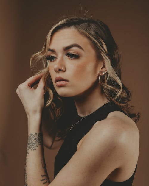 Free Woman in Make-Up and Tattoos Putting on Earrings Stock Photo