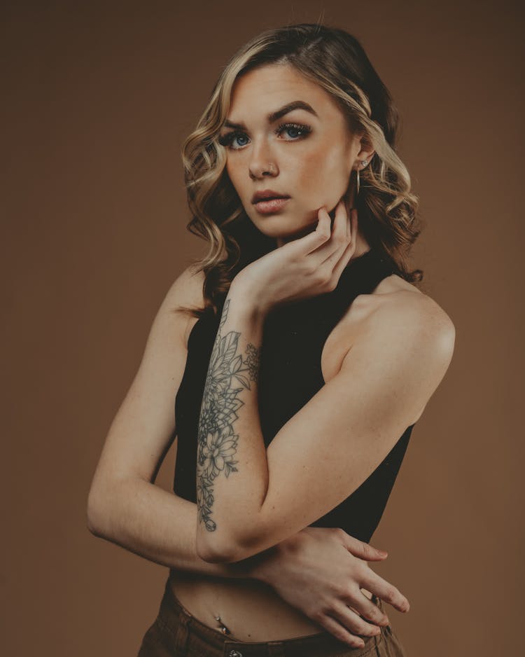 Woman With Tattoos With Her Hand On Jaw