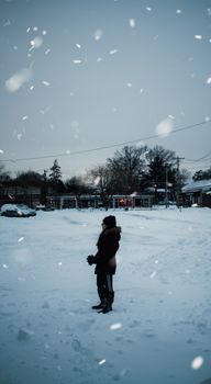 A person in winter clothing stands amidst snowfall on a New York street