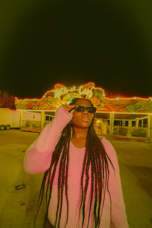 Woman in Pink Sweater Wearing Sunglasses at Night Time