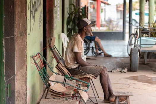 An elderly man sitting outside on a porch, reflecting in a rustic, rural setting.