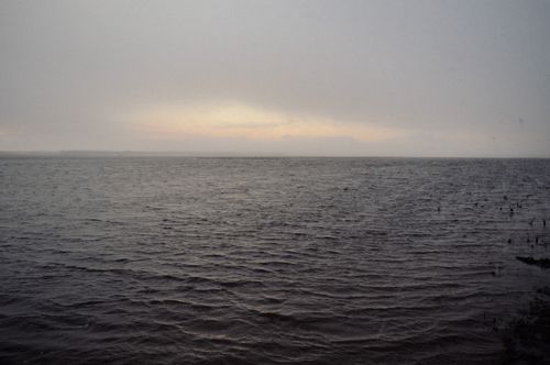 Free Serene view of a calm ocean stretching to the horizon during twilight, with a hazy sky. Stock Photo