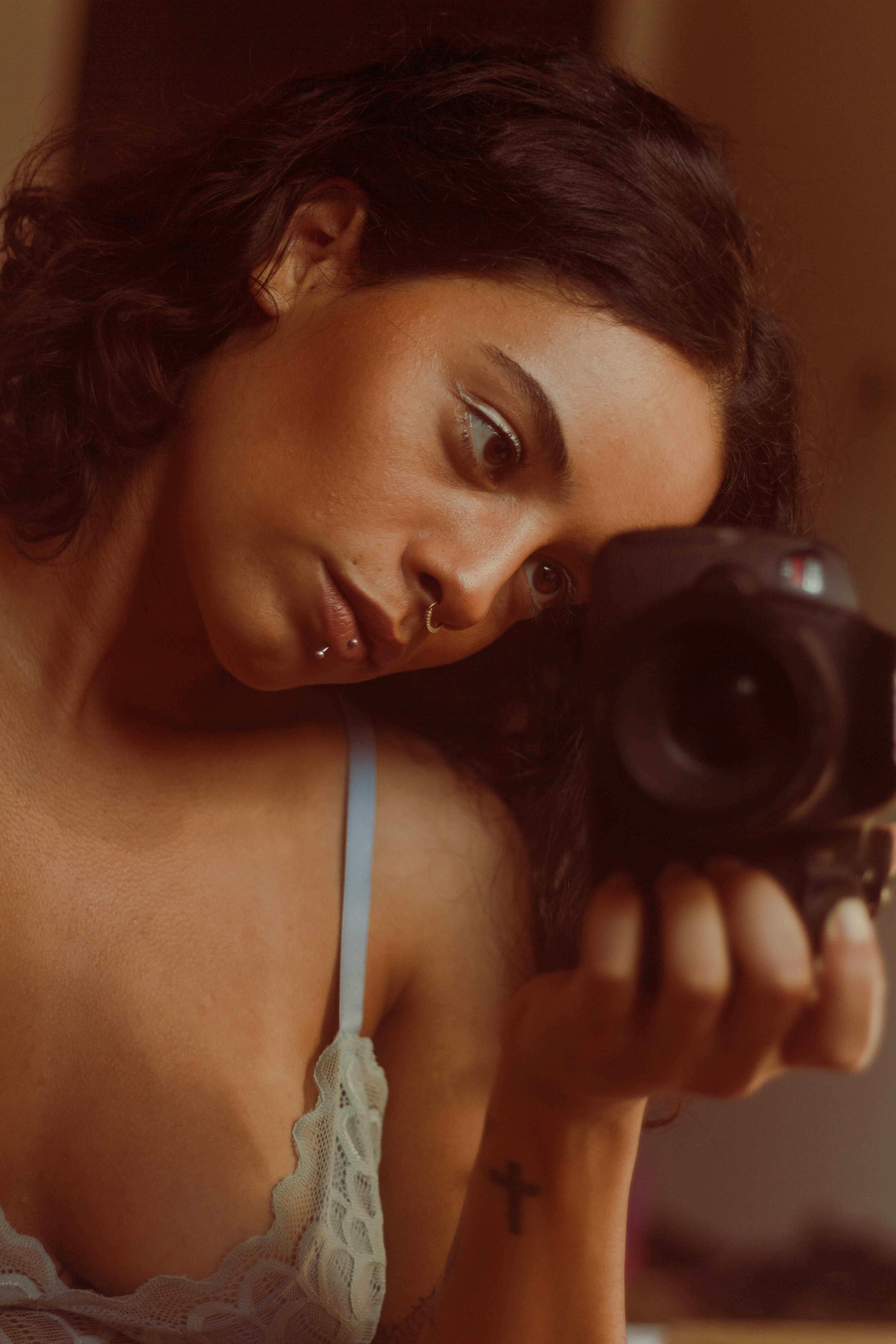 Portrait of a woman capturing her reflection with a camera.