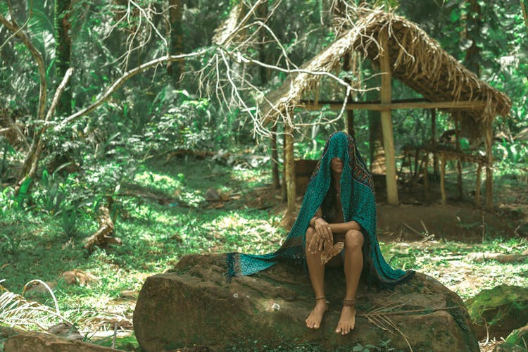 Woman Sitting On Rock With Veil On Head