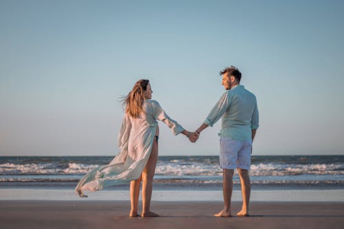 Free Photograph of a Couple Holding Hands on a Beach Stock Photo