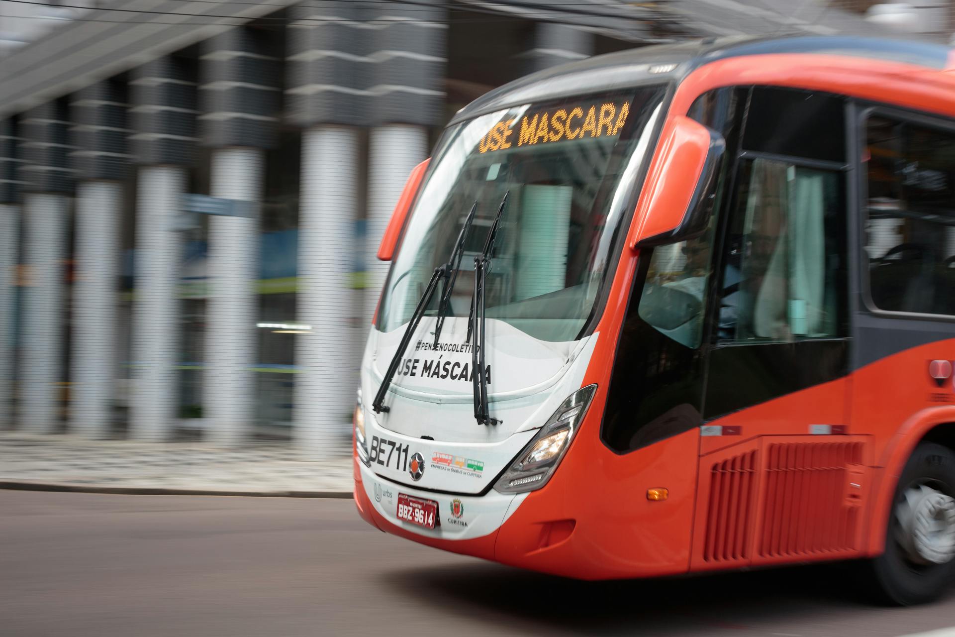 Red city bus speeding through urban area showcasing public transport efficiency.