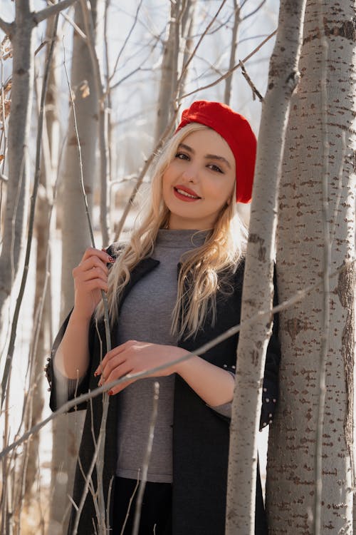 Photo of a Woman with Blond Hair Standing Beside a Tree